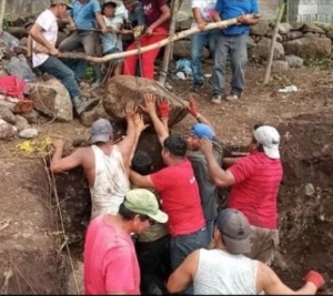 Crew lifts boulder from excavation
